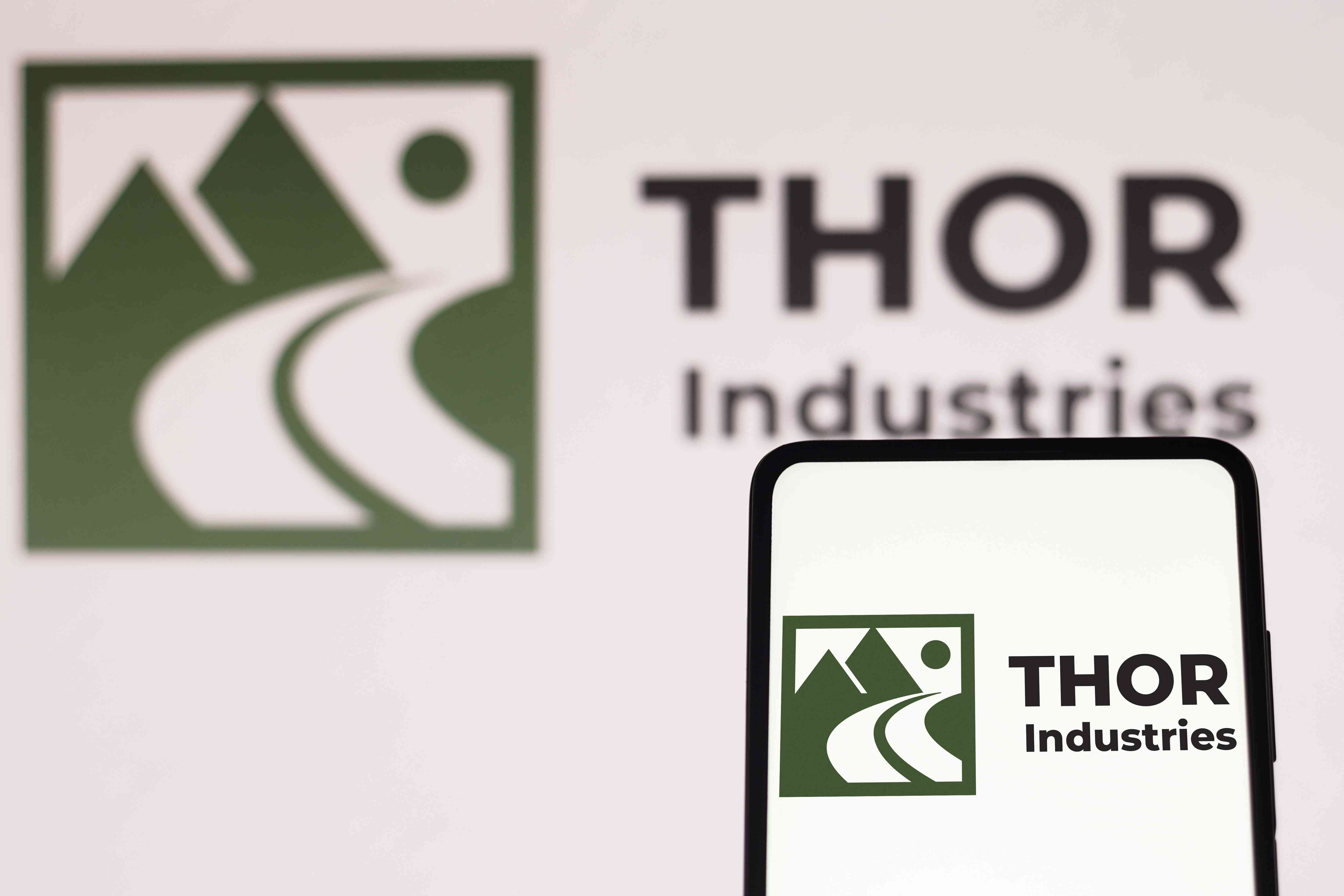 The Thor Industries logo is displayed on a smartphone screen and in the background