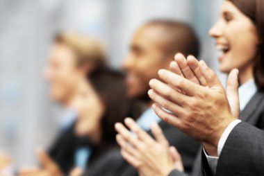 A group of business people smiling and clapping their hands