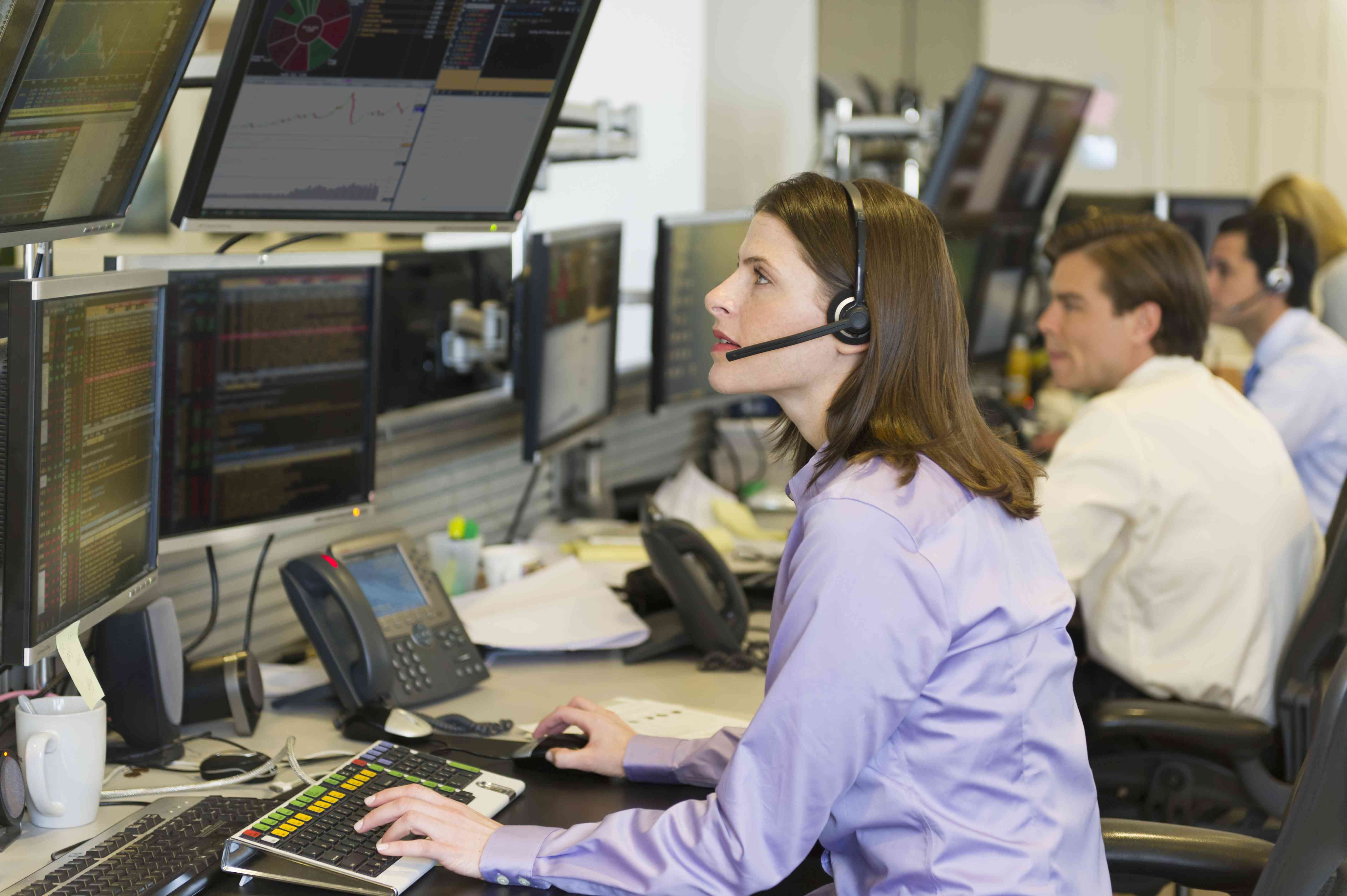 A woman sitting at a stock exchange trading desk 