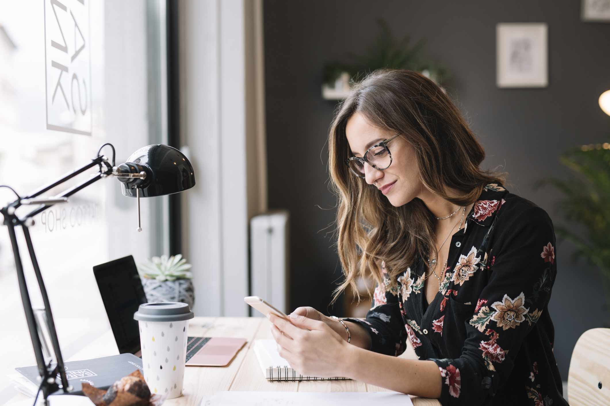 A woman uses her phone at a desk.