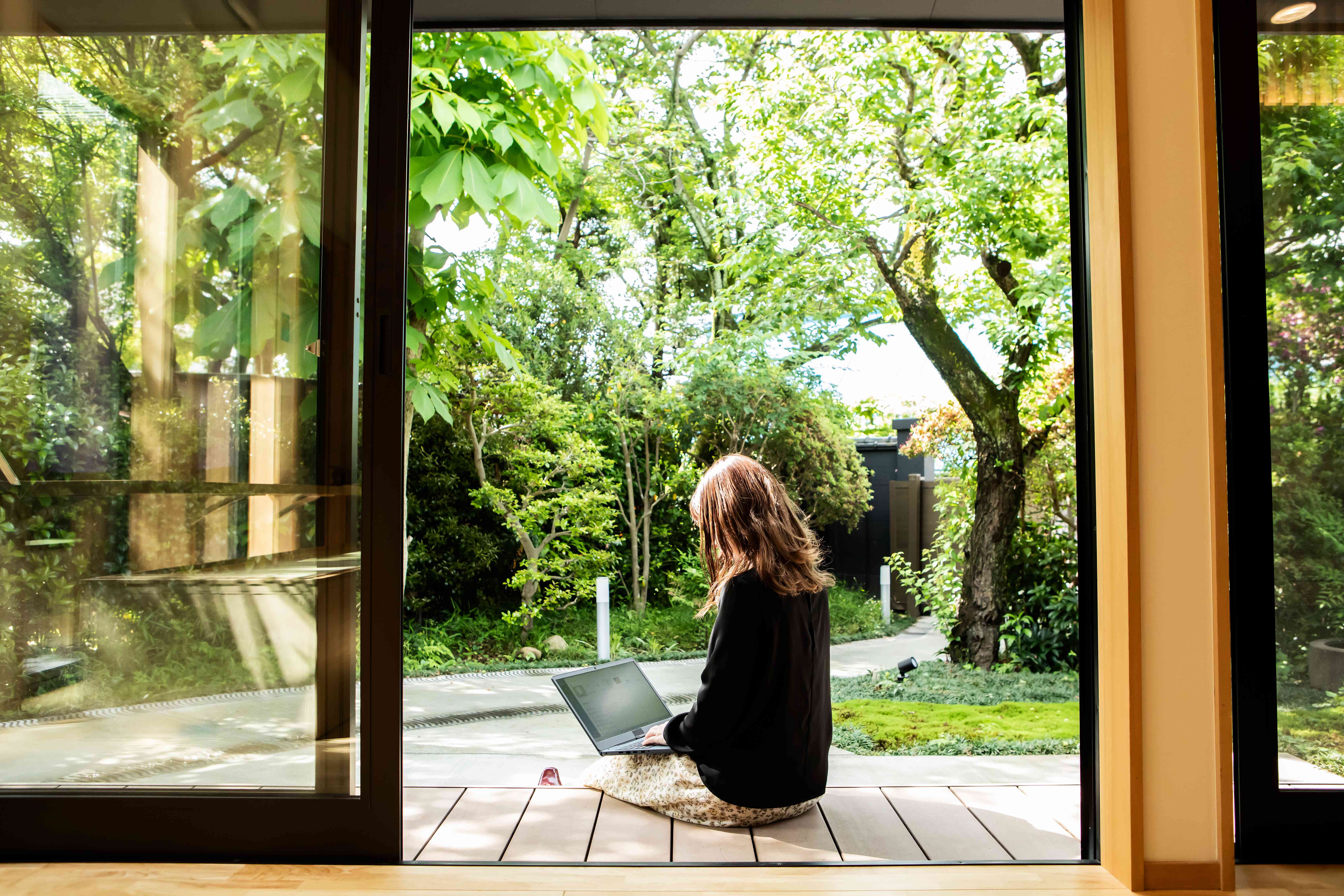 Woman sitting outside in greenery.