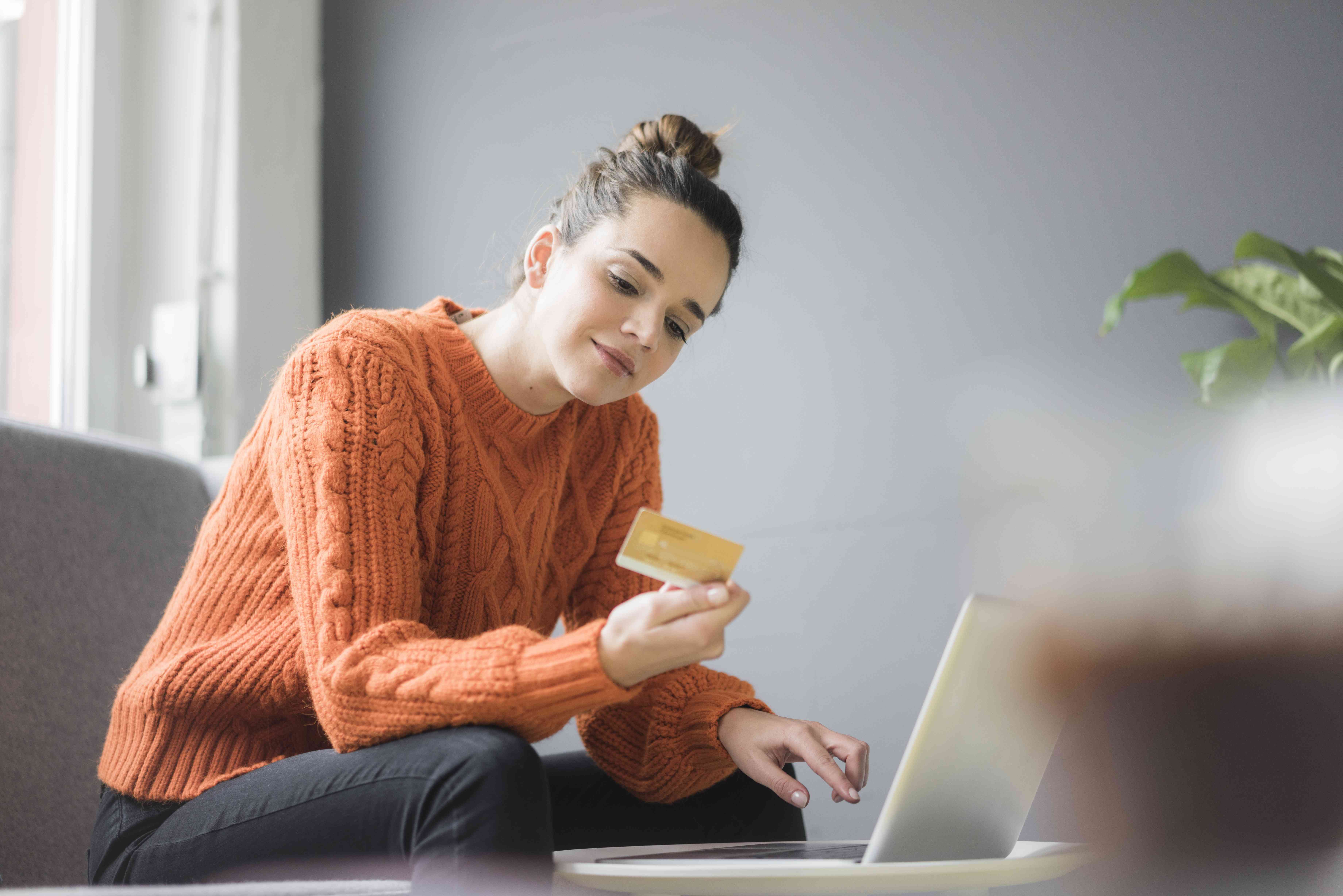 A person uses a credit card with a laptop.