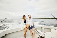 Wide shot of smiling couple sitting on stern of sport fishing boat