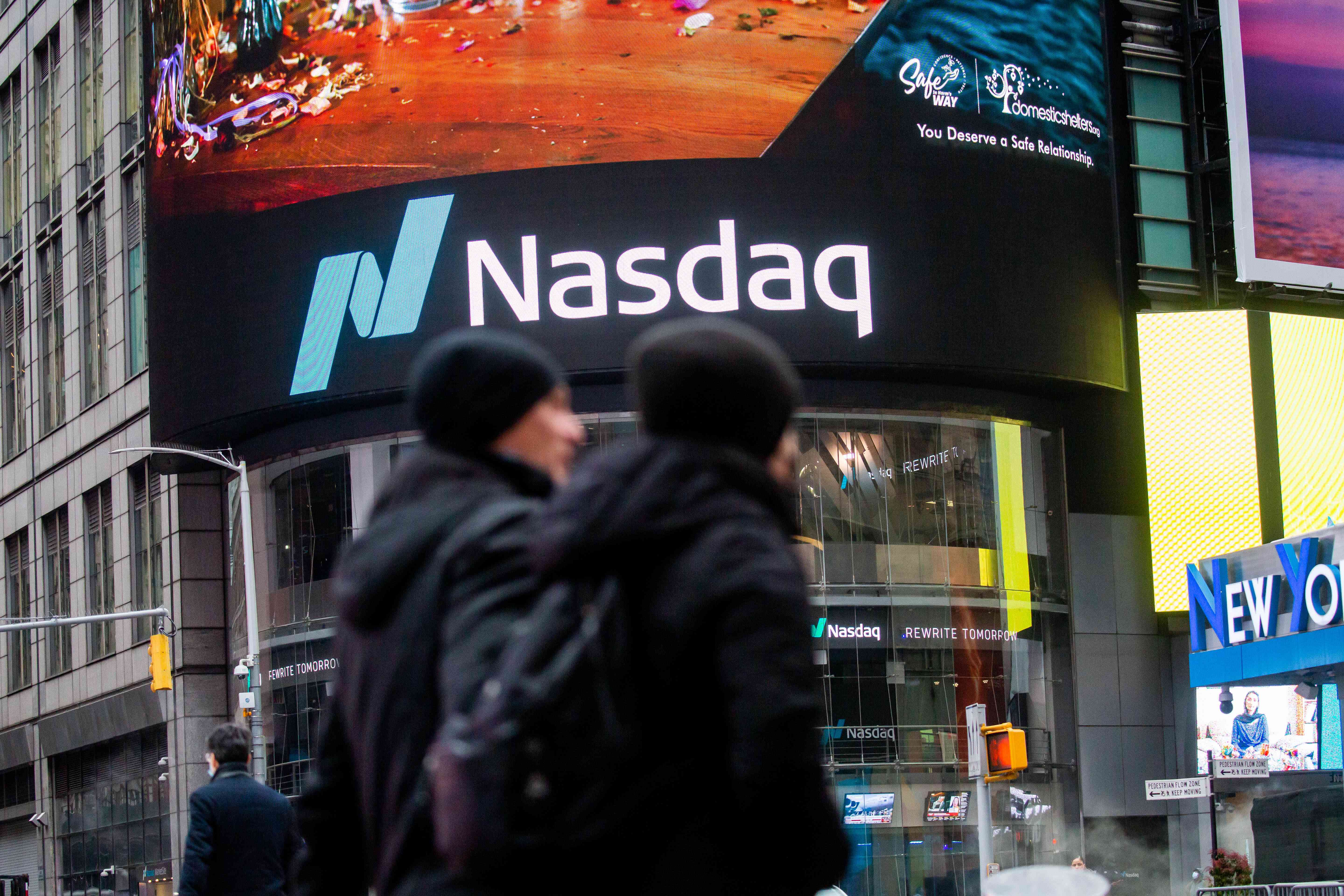 People walking outside NASDAQ building and sign.